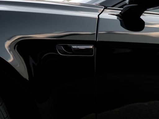 Glossy finish on a black sedan after wax and protection.